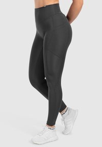 Leggings neri a vita alta con una texture liscia, dotati di tasche laterali e cuciture piatte per comfort e supporto.