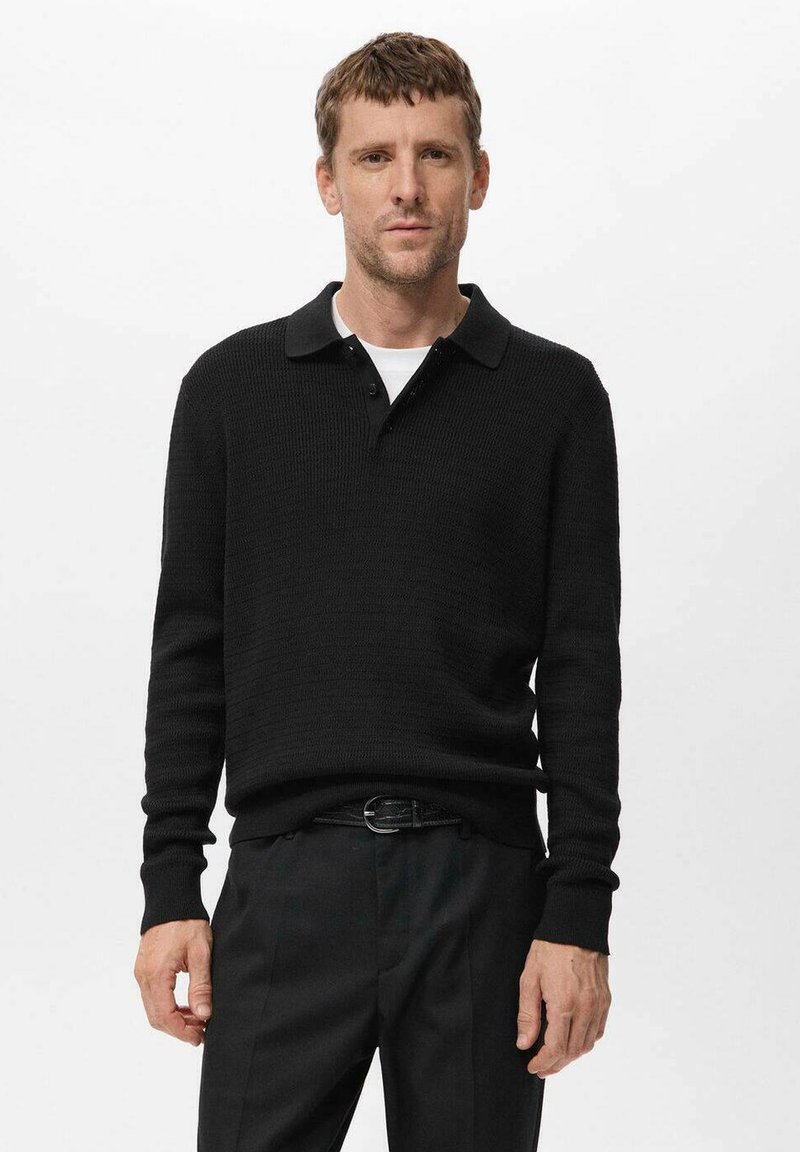 Suéter de polo negro de punto con cuello, textura acanalada y tapeta de botones, combinado con pantalones negros de corte ajustado.