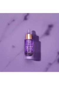 Bottiglia di siero in vetro viola con pipetta, tappo dorato e testo bianco, etichettata "Siero di Luce Cristallizzata Crystallove." Ombra su sfondo viola chiaro.