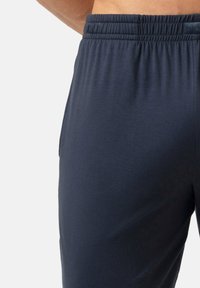 Marineblauwe sportbroek met elastische tailleband, gladde textuur en een ontspannen pasvorm, ideaal voor casual of actieve kleding.