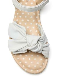 Sandal in pelle bianca con dettaglio a fiocco annodato. Soletta beige con motivo a stelle bianche. Cinghia regolabile per una vestibilità sicura.