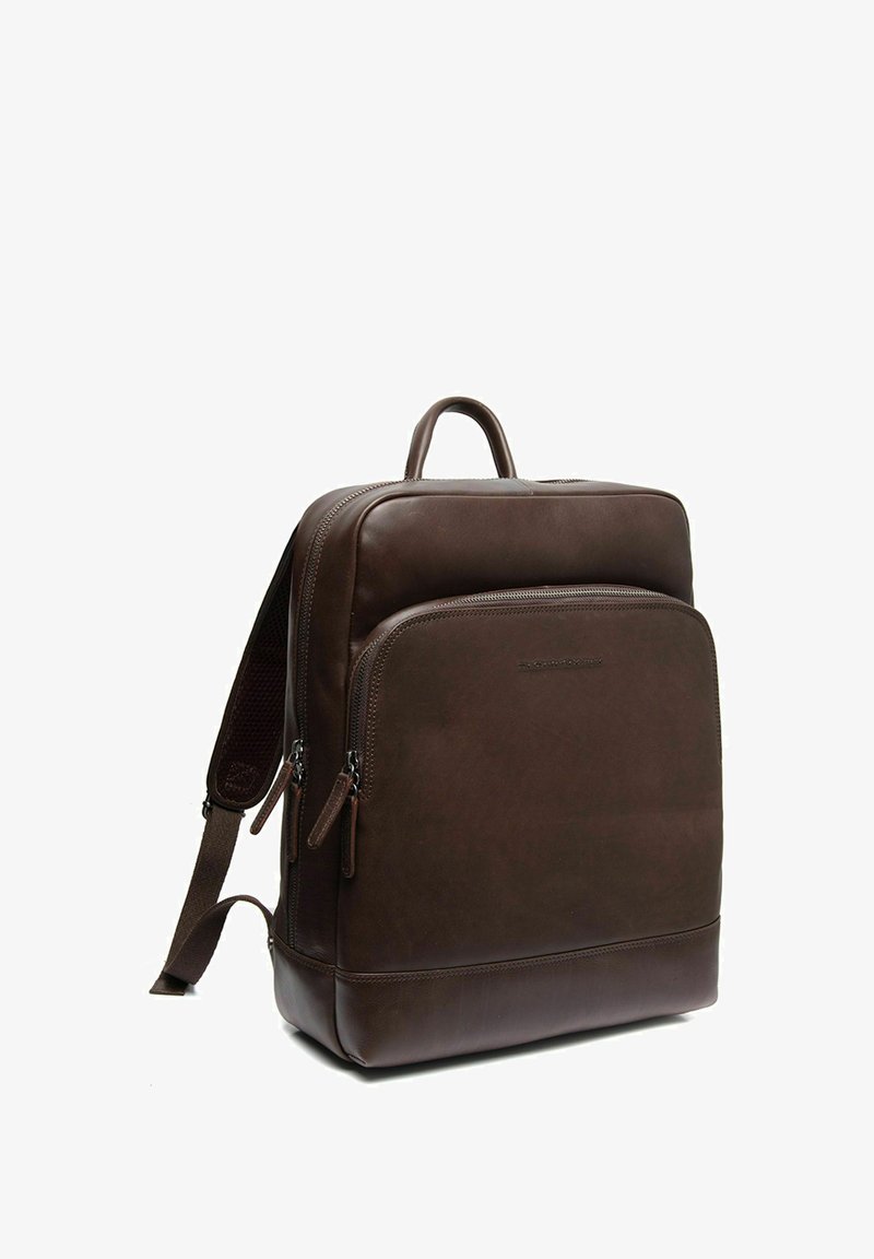 Brown leather backpack with a smooth texture, top handle, adjustable straps, front zip pocket, and minimalist design.
