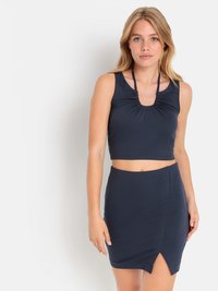 Merivärinen crop top, jossa on rypytetty yksityiskohta kauluksessa ja nauhat kaulalla; hyvin istuva minihame sivuräystäillä; sileä, joustava kangas.