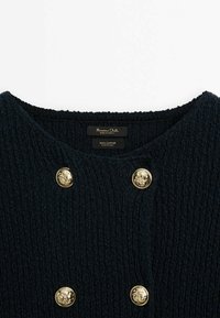 Granatowy bawełniany sweter z teksturowanym splotem, wyposażony w złote guziki w kształcie lwa i szeroki dekolt. Etykiety widoczne wewnątrz kołnierza.