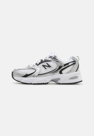 Silver and white athletic shoe with mesh upper, black accents, round toe, and textured rubber outsole. Features "ABZORB" cushioning technology.