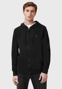 Felpa nera con zip, cappuccio regolabile, tasche frontali e un piccolo emblema sul petto. Realizzata in un morbido tessuto testurizzato.