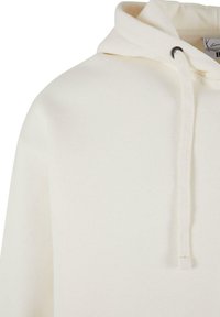Lys beige hettegenser med snor, myk tekstur og avslappet design. Har en rund halslinning og ingen synlige logoer.