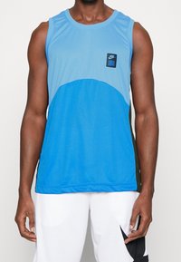 Canotta sportiva blu con design arrotondato, dotata di texture a rete, toppa con logo Nike nera e accenti laterali verde scuro a contrasto.