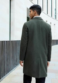 Dunkelgrüner Wollmantel mit geradem Schnitt, Reverskragen und langen Ärmeln. Verfügt über einen einzelnen Schlitz und saubere Nähte für einen maßgeschneiderten Look.