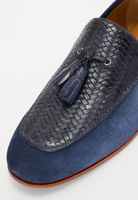 Loafers bleu marin cu partea superioară din piele țesută, vamp din nubuc și ciucuri decorative. Prezintă talpă din cauciuc și talpă exterioară contrastantă maro.