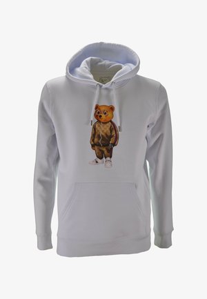 Felpa bianca con un orso stampato che indossa occhiali, tuta marrone, un orologio e sneaker bianche al centro della parte anteriore.