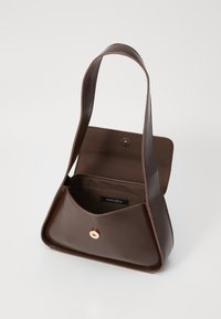 Brown leather handbag with a structured shape, a single flat handle, snap closure, and an interior label marked "ANNA FIELD."