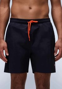 Tengerészkék úszónadrág elasztikus derékkal és narancssárga húzózsinórral. Könnyű anyag, sima tapintással. Kicsi logó részlet az oldalon.