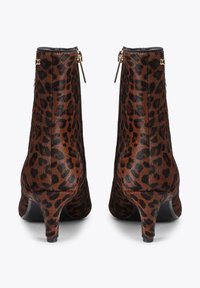 Botki na kostkę w panterkę z teksturowanym brązowo-czarnym wzorem, z niskim obcasem, zapięciem na zamek błyskawiczny i smukłą sylwetką.