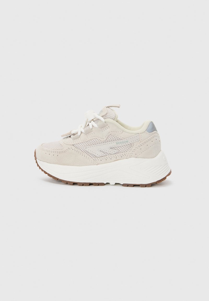 Beige sneakers med mesh- og semsket overdel, med en hvit mellomsåle, brun gummisåle og kontrasterende grå aksenter på hælen.
