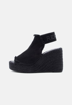 Sandale espadrille noire à talon compensé, bords effilochés et bride arrière élastique, avec semelle plateforme tissée texturée.