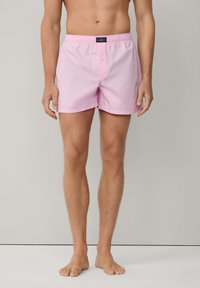 Rosa badshorts med elastisk midja och knappframsidan. Tillverkade av lättviktsmaterial, med en slät textur och en längd ovanför knäna.