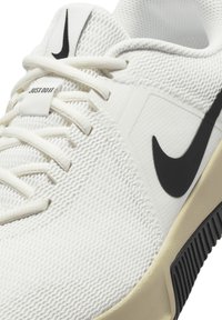White athletic shoe with a textured upper, featuring black Nike swoosh and "Just Do It" label, complemented by a black sole.