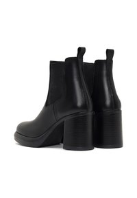 Botas de cuero negras hasta el tobillo con punta redonda, paneles laterales elásticos y tacones gruesos texturizados. Presenta dos tiradores para ponerlas y quitarlas fácilmente.