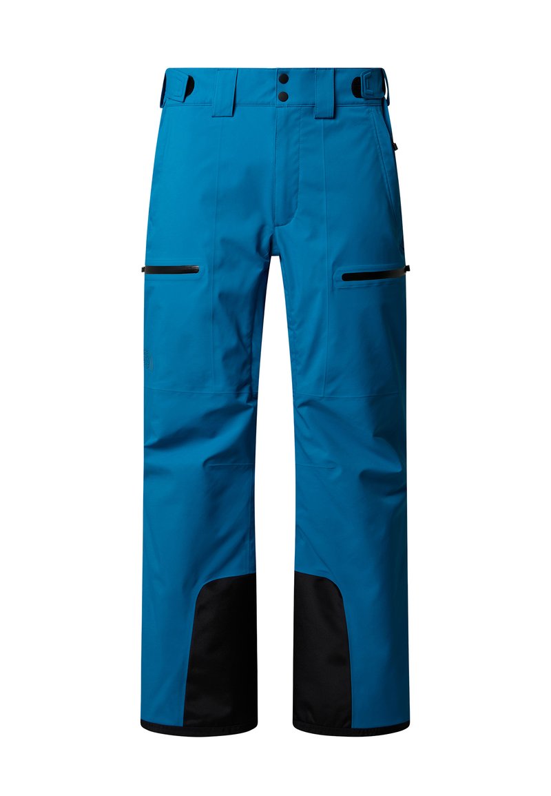 Pantaloni da esterno blu con linguette laterali regolabili, toppe nere rinforzate sulle gambe inferiori e tasche orizzontali con zip sulle cosce.