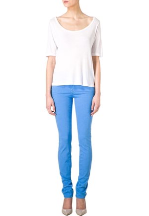 Top blanco de manga corta y jeans ajustados de mezclilla azul claro, fabricados en algodón, con una textura suave y un diseño ajustado, llevados con zapatos de punta beige.