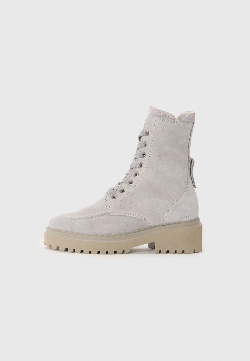 Hellgraue Wildleder-Ankle Boots mit runder Spitze, Schnürung vorne und dicker beiger Sohle. Mit goldfarbenen Ösen und einer Zuglasche an der Ferse.