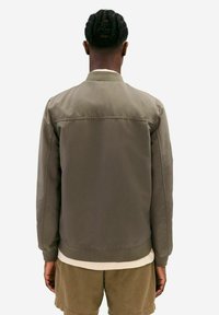 Olive green bomber jacket with a smooth texture, ribbed cuffs, and hem. Features a simple design with no visible hardware or embellishments.