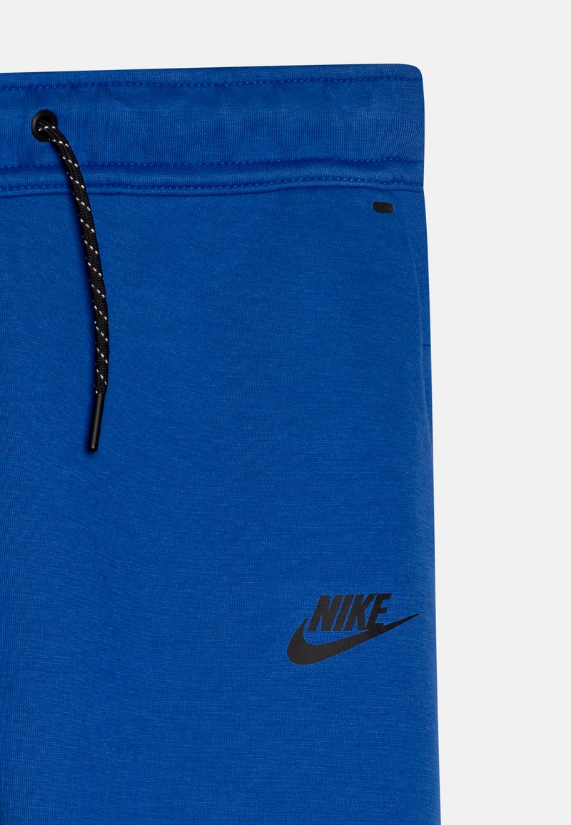 Blaue Jogginghosen aus weichem Stoff, mit einem schwarzen Kordelzug und einem kleinen schwarzen Nike-Logo an der Seite. Glatte Textur, lässige Passform.
