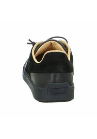 Schwarzer Wildleder-Sneaker mit einer strukturierten Gummisohle, weicher beiger Innenausstattung und minimalistischem Design, ausgestattet mit einem Logo auf der Ferse und Schnürung.