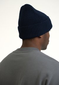 Gorro de punto acanalado en color marino con un extremo puntiagudo, usado sobre una sudadera gris. El gorro tiene una textura suave y un ajuste ceñido.