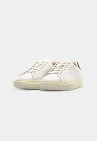 Sneakers bianchi in pelle con punta arrotondata, suola in gomma spessa di colore crema e design minimalista. Presentano lacci e un logo discreto sulla linguetta.