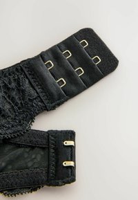Cinghia di reggiseno nera con bordino in pizzo, dotata di chiusura a gancio e asola, hardware metallico dorato e tessuto testurizzato.