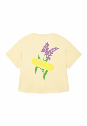 Geel kortarmige shirt met een grafisch ontwerp van paarse bloemen en een gele pleister op de rug. Zachte stof met een losse pasvorm.
