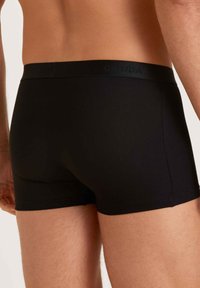 Boxer shorts in cotone nero con una cintura morbida, caratterizzati da un design semplice e da una forma aderente che si adatta al corpo.