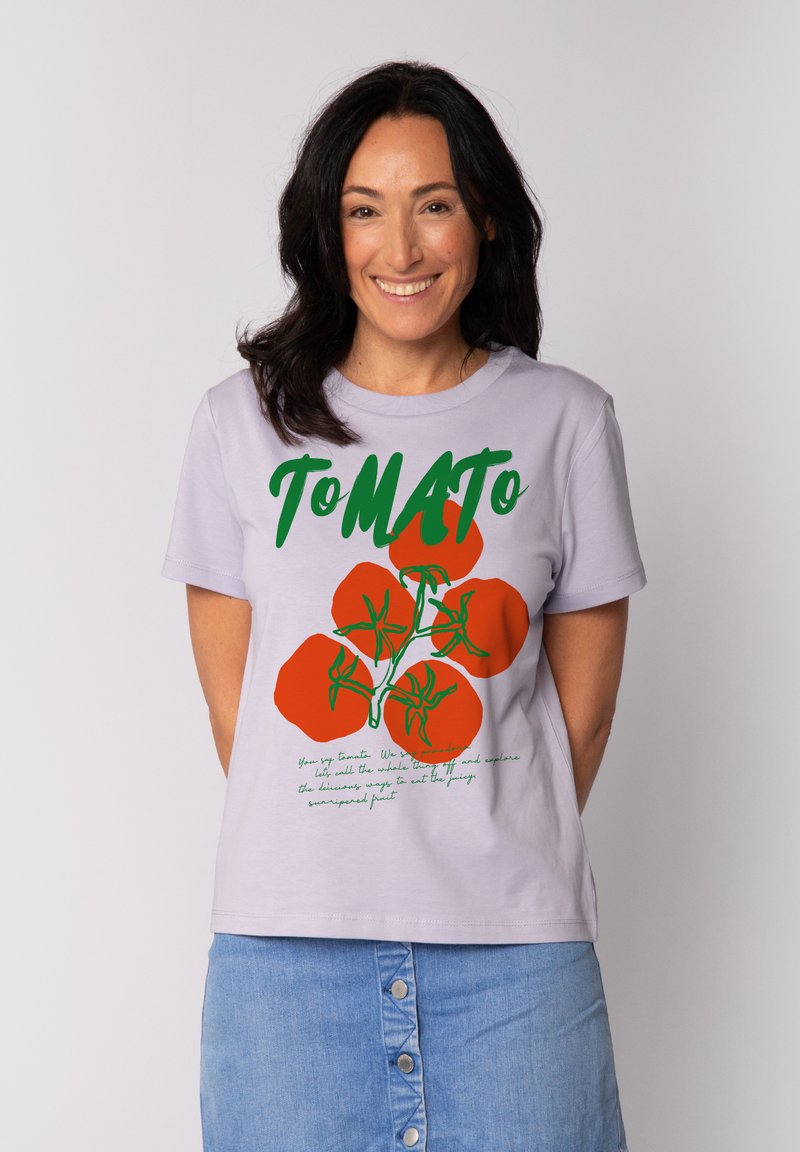 Lichtpaarse katoenen t-shirt met een opvallende grafische afbeelding van rode tomaten en groene tekst. Korte mouwen en een ronde halslijn met een rechte zoom.