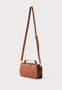Bolsa de ombro de couro marrom com detalhes em dourado, forma retangular, alça curta na parte superior e correia ajustável e destacável. Textura suave com fecho de aba.
