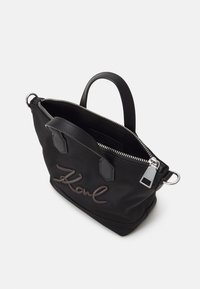 Czarna torba na ramię wykonana z nylonu, z srebrnym zamkiem, małymi czarnymi skórzanymi uchwytami i haftowanym logo "Karl" z przodu.