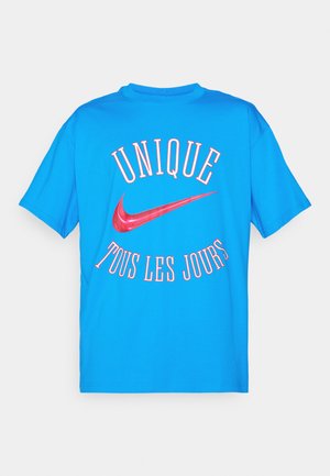 Μπλε βαμβακερό T-shirt με κόκκινη επιγραφή "UNIQUE TOUS LES JOURS" και το κόκκινο λογότυπο της Nike στο πίσω μέρος, κοντά μανίκια, σχεδίαση με στρογγυλή λαιμόκοψη.