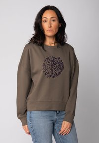 Bruine sweatshirt met een relaxed fit, voorzien van een paarse grafische afbeelding van een brein en bloemelementen. Lange mouwen, geribde manchetten.