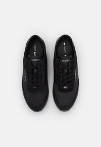 Schwarze Sneakers mit einem strukturierten Mesh-Obermaterial, runder Zehenpartie, Schnürdesign und Logo-Details an der Zunge und an der Seite. Gummisohle für besseren Halt.