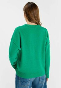 Groene, oversized trui met ronde hals, verlaagde schouders en geribbelde boorden. Zachte, gestructureerde stof, gecombineerd met loszittende denim jeans.
