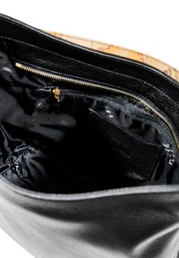 Borsa in pelle nera con esterno testurizzato. Ha un compartimento con zip e un interno in tessuto nero liscio con tasche.