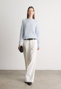 Světle modrý svetr, bílé nohavice širokého střihu, černý pásek a černá kabelka. Hladká textura, dlouhé rukávy a výstřih ve tvaru lodě.