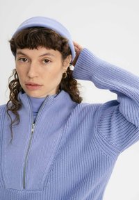 Lichtpaarse gebreide trui met rits en textuur ribbels, met lange mouwen en een bijpassende beanie. Glad materiaal, casual ontwerp.