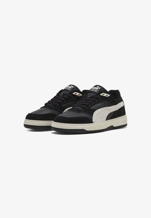 Sneaker in suede nero e crema con una striscia bianca testurizzata, lacci neri e suole in gomma caratterizzate da un logo discreto sulla linguetta.