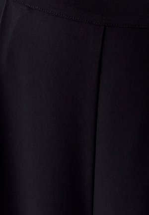 Črn material s osrednjo vertikalno šivom in horizontalnim šivom blizu vrha, ki prikazuje teksturo in podrobnosti šivanja.