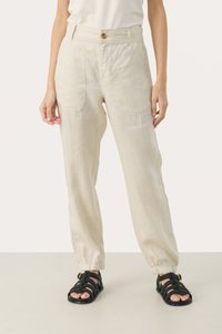 Light beige linen trousers with a relaxed fit, featuring side pockets and elastic cuffs, paired with strappy black sandals.