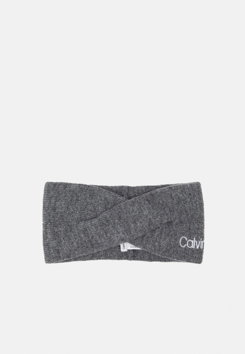 Bandeau en tissu gris tricoté avec un devant torsadé et le logo Calvin Klein partiellement visible sur un côté.
