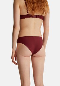 Bikini-Höschen in Burgunderrot mit glatter Textur, niedrigem Schnitt und minimaler Abdeckung, entworfen für Komfort und eine schlanke Silhouette.