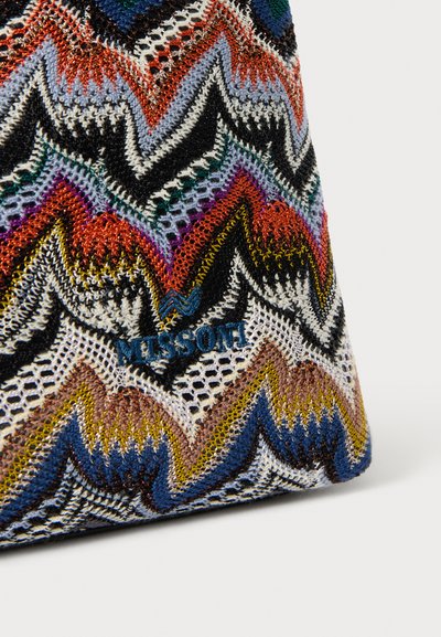 Wielokolorowa torebka pleciona w zygzakowaty wzór w kolorach czerwonym, czarnym, białym, żółtym i niebieskim, z niebieskim logo "Missoni" wplecionym w tkaninę.